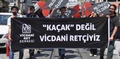 Davut Erkan (solda) vicdani ret eyleminde, “Kaçak değil vicdani retçiyiz” pankartını taşırken.